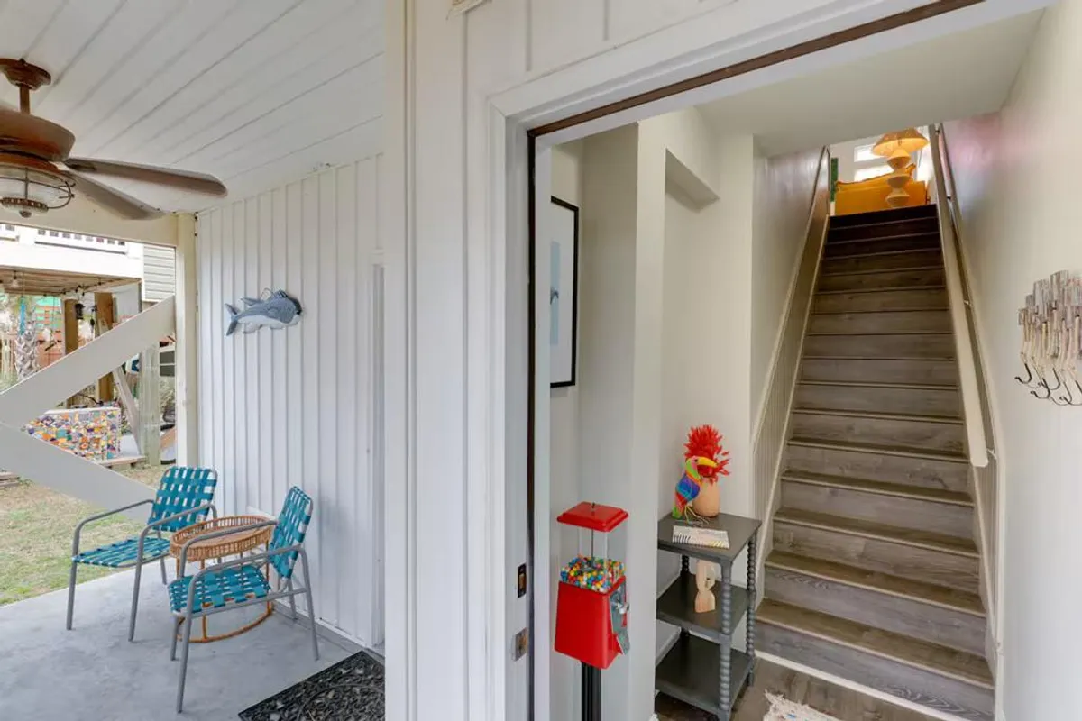 A whimsical entry space with colorful chairs, a staircase, playful decor, and a gumball machine creates a cheerful first impression. The area is clearly marked and welcoming, suggesting easy and inviting arrivals for guests.