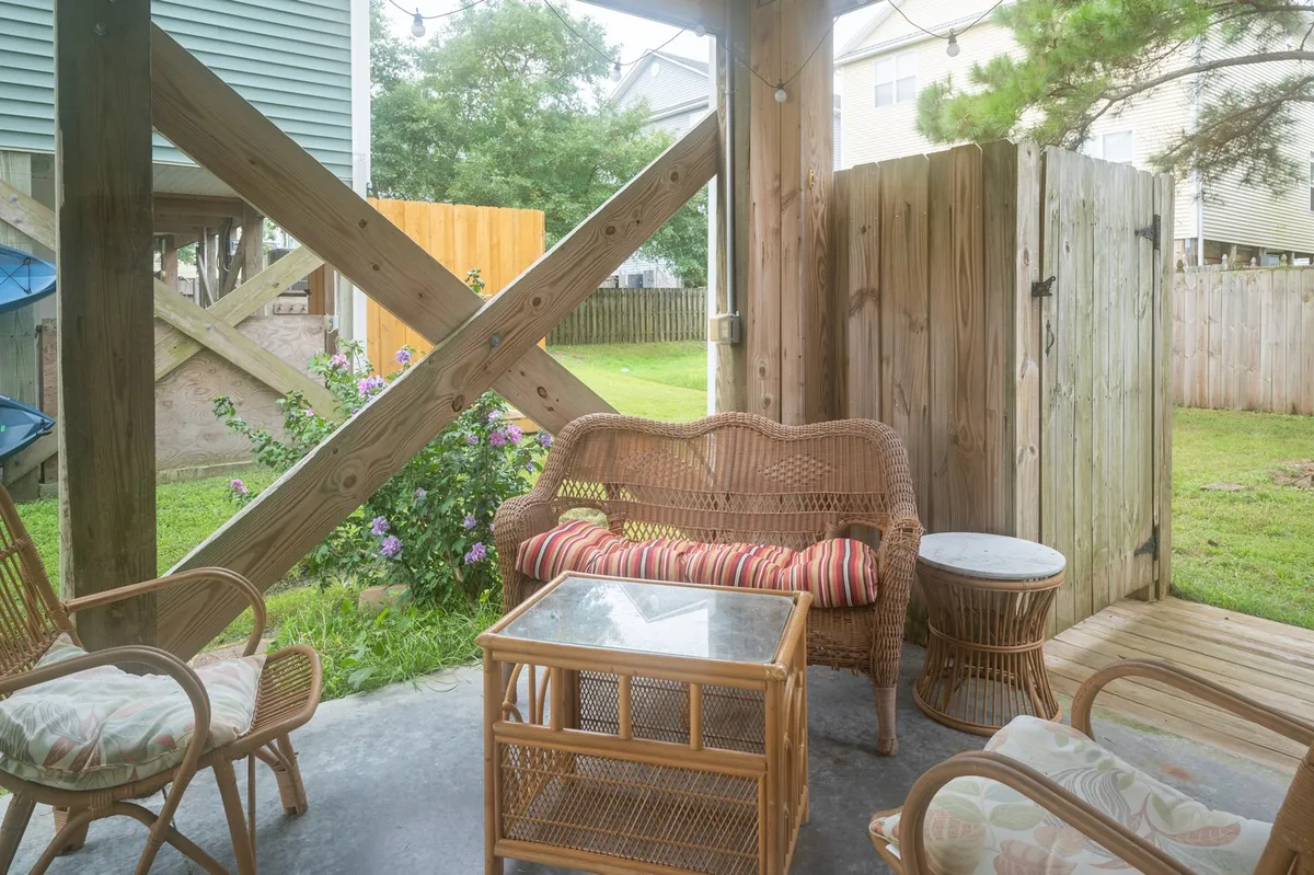 The exterior scene presents a cozy wicker sofa and glass coffee table set on a green lawn, hinting at a comfortable spot for relaxing, entertaining, or enjoying nature. The seating is positioned to make the most of sunset views and outdoor gatherings.
