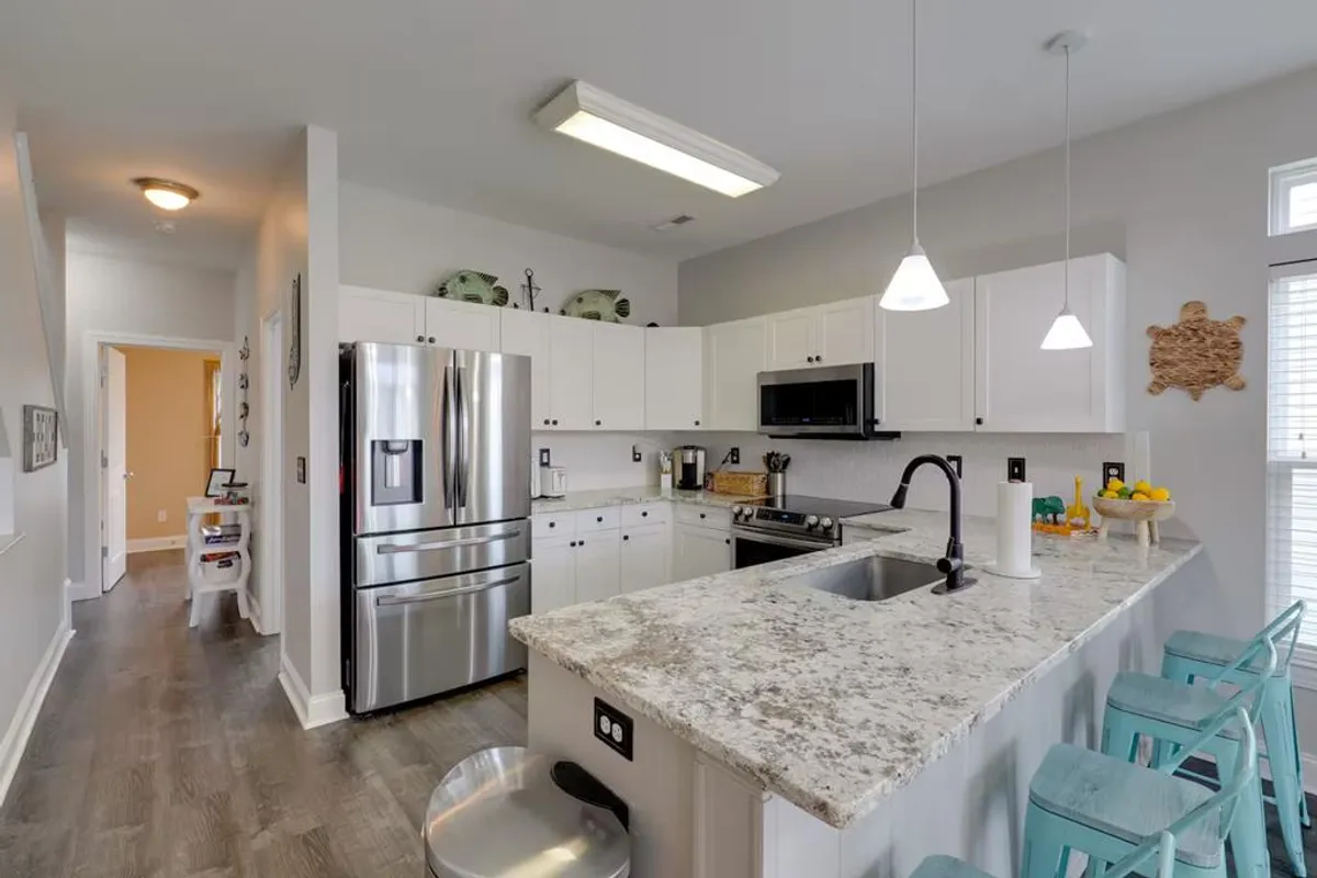 A modern kitchen with granite countertops, stainless steel appliances, and bar stools at a kitchen island. The layout is open and welcoming, suited for cooking, entertaining, and group meals with plenty of space for guests to gather.