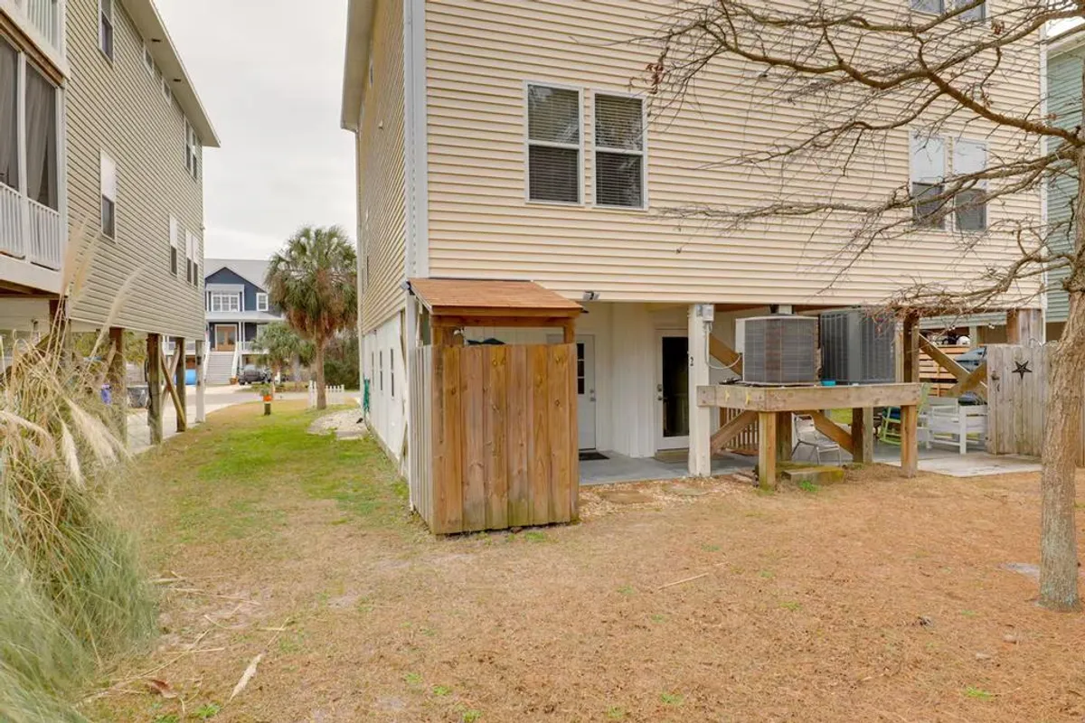 This exterior shot features the wooden structure of the duplexes, a pathway leading to the entrance, and neighboring buildings. The image exudes a welcoming, communal vibe and hints at the proximity to local attractions and gathering spots.